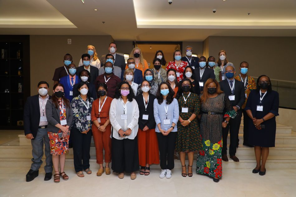 Group photo of individuals in business attire in front of steps of a conference center. Individuals are wearing face masks and event lanyards